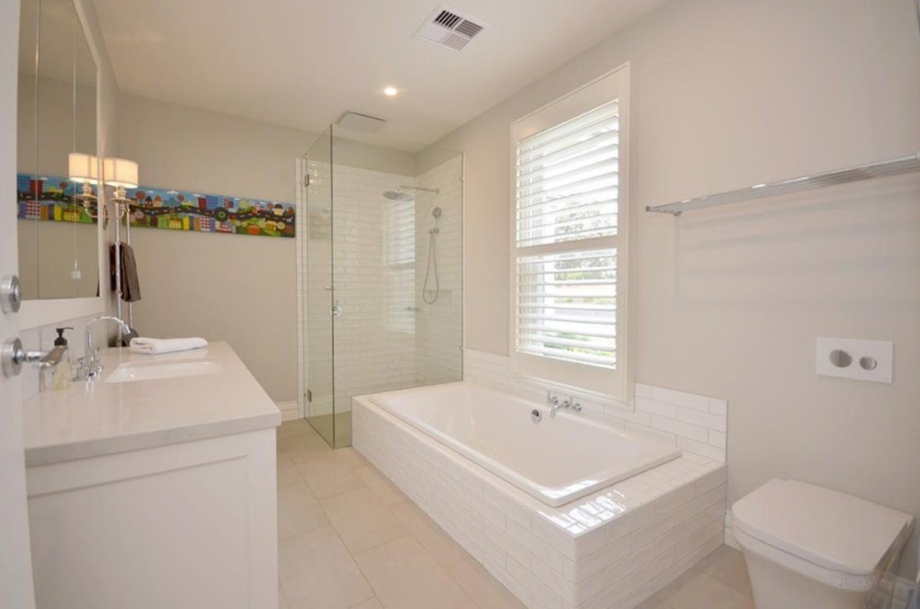 Family bathroom with built in bath, walk in shower and white vanity