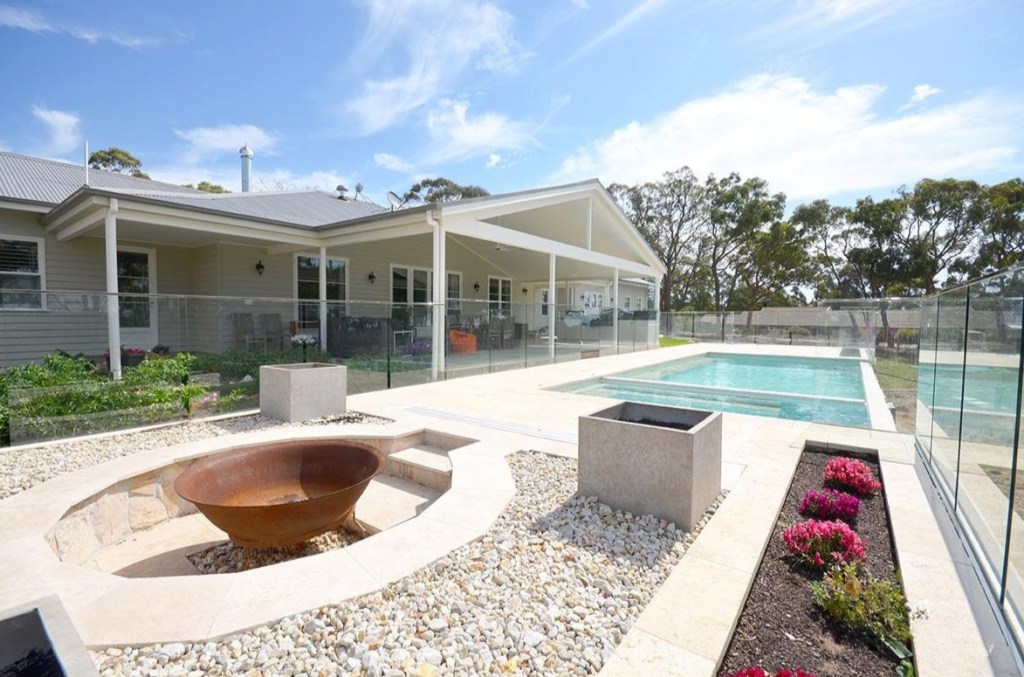 Outdoor pool area with fire pit and covered entertaining space