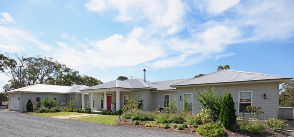 Country home exterior with grey weatherboards and landscaped gardens
