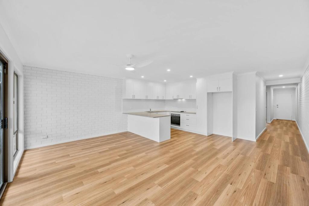 Completed unit renovation in Malua Bay showing a white kitchen, painted brick walls and timber-look flooring